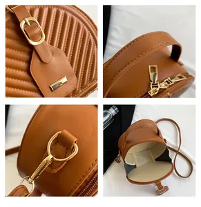 Close-up details of a stylish brown round crossbody bag with golden hardware accents.