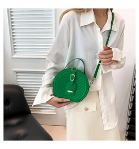 Fashionable green quilted round crossbody bag styled with a white shirt on model