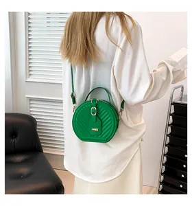 Back view of a stylish green circular crossbody bag worn by a model in a white shirt
