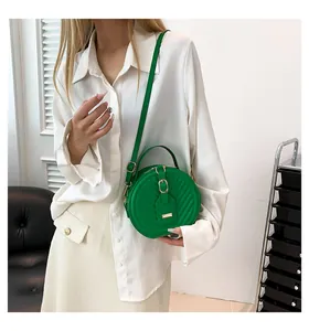 Elegant model shot of a green quilted round handbag with gold-tone hardware and strap