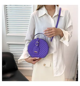 Fashionable purple round crossbody bag shown on a model in a clean indoor setting