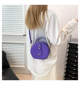 Fashionable woman wearing a purple round crossbody bag with quilted chevron texture