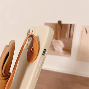 Close-up view showing the side detail of a cream phone case with a brown leather bow strap