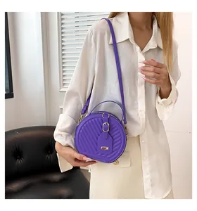 Chic purple quilted round crossbody bag shown on a model wearing a minimalist white shirt
