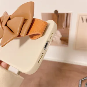 Close-up view of the phone case bottom charging port and leather bow wrist strap.