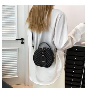 Rear view of model wearing a black quilted round crossbody bag over a white shirt.