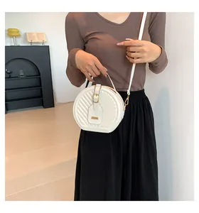 Detailed view of a stylish white circular crossbody bag with quilted chevron texture.