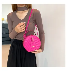 Detailed view of a bright pink circular quilted crossbody bag styled with an autumn outfit