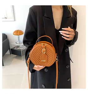 Model carrying a fashionable brown round crossbody bag with chevron pattern