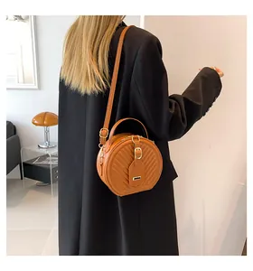 Stylish woman wearing a brown quilted round crossbody bag over a black wool coat