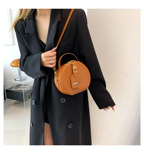 Close-up of stylish round orange crossbody bag worn with a black blazer for a chic look