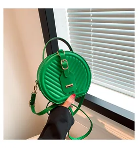 Close-up of a stylish green round crossbody bag with quilted texture and handle.