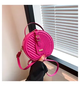 Fashionable hot pink quilted round crossbody bag for women shown in a detail view