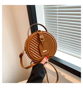 Detail view showing the brown quilted texture and golden hardware of the round bag