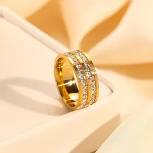 Close-up detail of a gold stainless steel ring with double rows of square crystals.