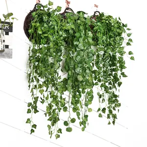 Detail view of 2M artificial ivy vines hanging on white slatted wall backdrop.