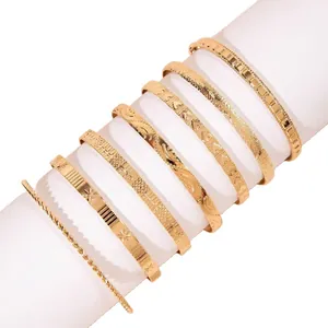 Set mit 7 goldfarbenen, stapelbaren Metallarmreifen mit ethnischen Mustern