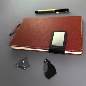 Set of cute black cat magnetic bookmarks displayed on a notebook and table