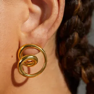 Gold spiral stud earrings made of high-polished stainless steel worn on ear.