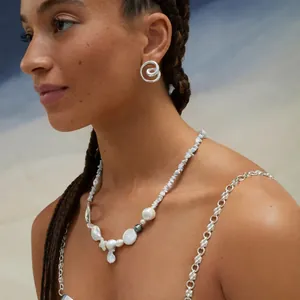 Elegant stainless steel spiral stud earrings worn by a professional model at the beach