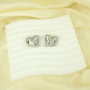 Macro view of silver metallic heart-shaped stud earrings on a display tray.