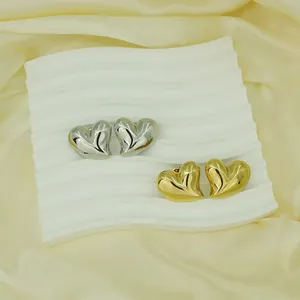Detailed view of silver and gold stainless steel textured heart-shaped stud earrings