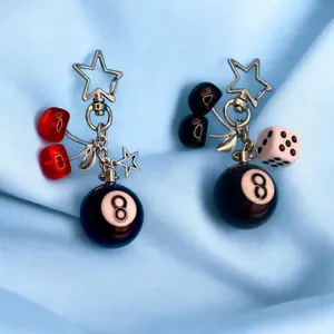 Detailed close-up of resin cherry and 8-ball charms on a star-shaped silver keychain.