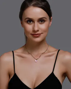 Close-up detail of an elegant pink butterfly pendant necklace worn by a female model.