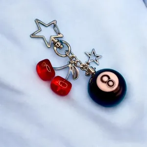 Detailed close-up view of a cherry and 8-ball resin keychain with a star-shaped silver clasp