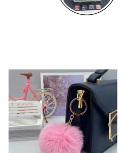 Close-up detail of a soft 8cm pink faux fur ball keychain on a navy blue handbag.
