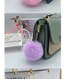 Detailed shot of an 8cm purple faux rex rabbit fur ball keychain on a handbag.