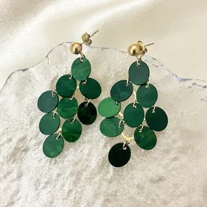 Close-up detail of stylish green multi-layer disc tassel earrings on a glass prop