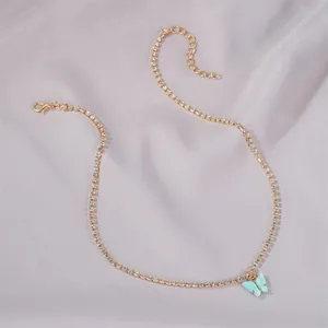 Detail view of a dainty gold necklace with a light blue butterfly pendant and rhinestones