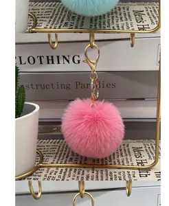 Detailed view of a soft pink faux fur pom-pom keychain with gold lobster clasp