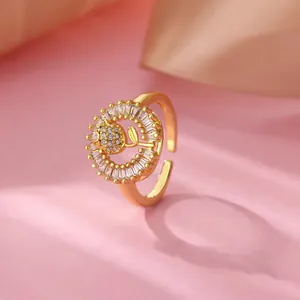 Gros plan d'une bague dorée avec un motif de rose en zircon et halo de cristaux étincelant.