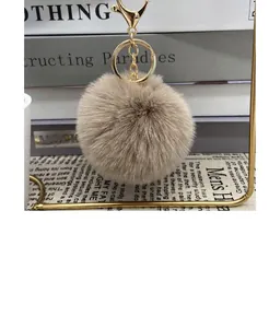 Detail view of a soft 8cm tan faux fur pom-pom keychain featuring elegant gold hardware
