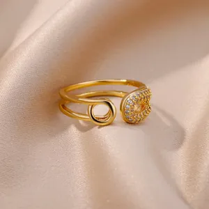 Gros plan d'une bague double couche dorée ornée de zircons avec motif épingle à nourrice