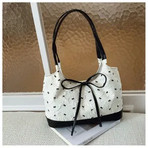 Chic white underarm bag with a prominent black bow and delicate ribbon patterns