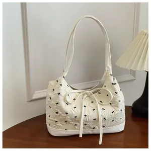 Macro view showing the textured fabric and black bow pattern on cream white shoulder bag