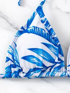 Dettaglio ravvicinato di un top bikini bianco con stampa di foglie tropicali blu