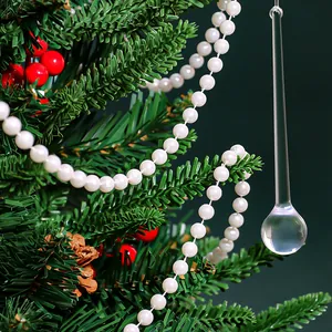 Close-up of a clear glass icicle ornament hanging on a decorated Christmas tree