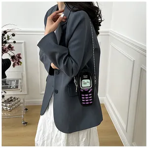 Detail view of a stylish novelty phone-shaped mini crossbody bag worn with a grey blazer.