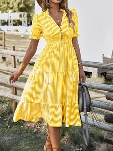 Detail view of summer yellow and white striped V-neck tiered midi dress worn by a model outdoors.