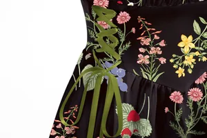 Close-up view of an elegant black floral dress featuring olive green ribbon lace-up detail