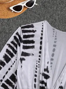 Dettaglio del copricostume in rete bianca con stampa tie-dye nera e motivi testurizzati.