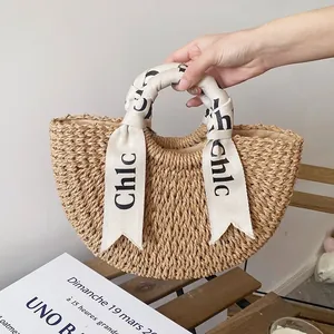 Handmade straw woven semicircular handbag with ribbon wrapped handle for beach vacation