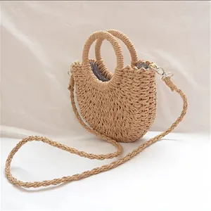Side angle view of a semi-circular straw woven bag showing texture, handles and strap