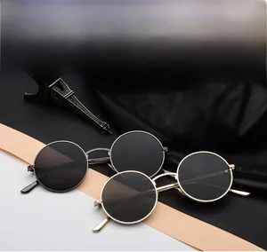 Detail view of retro metal round frame sunglasses with dark lenses on textured leather