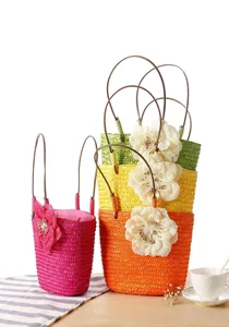 Detailed view of colorful handmade straw woven bags with decorative floral accents.