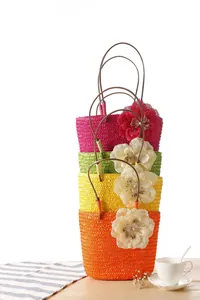 Detailed shot of stacked colorful woven straw bags with large fabric flowers